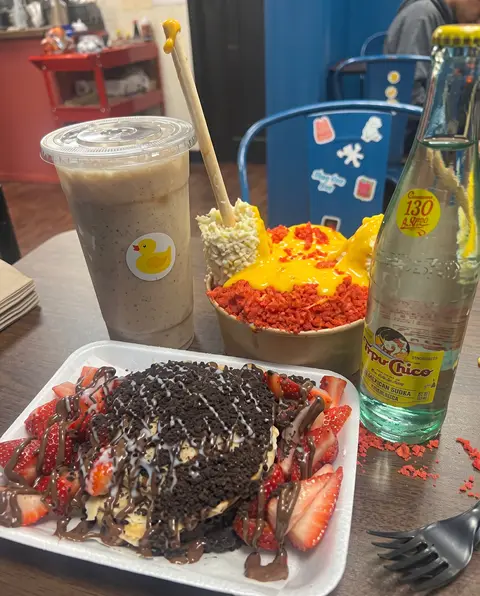 Un frappé Poloco, una mangonada con chips picantes y un Topo Chico junto a un postre cubierto de Oreo con fresas