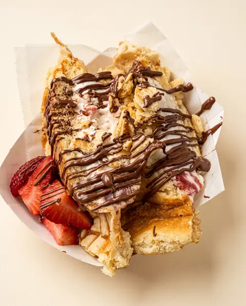 Un waffle con crema batida, fresas frescas y Nutella derretida