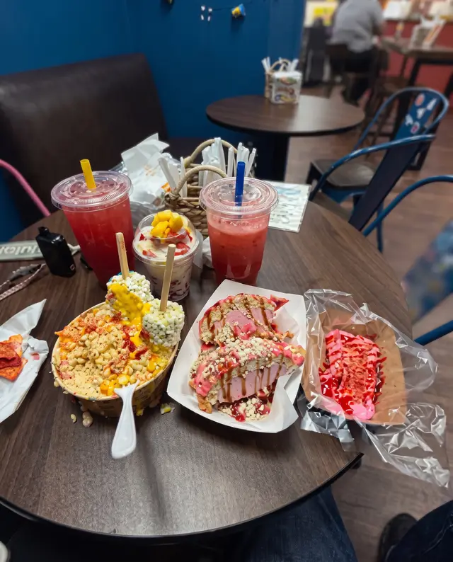 Una mesa dentro de Poloco con aguas frescas, esquites y postre, rodeada de sillas azules de metal